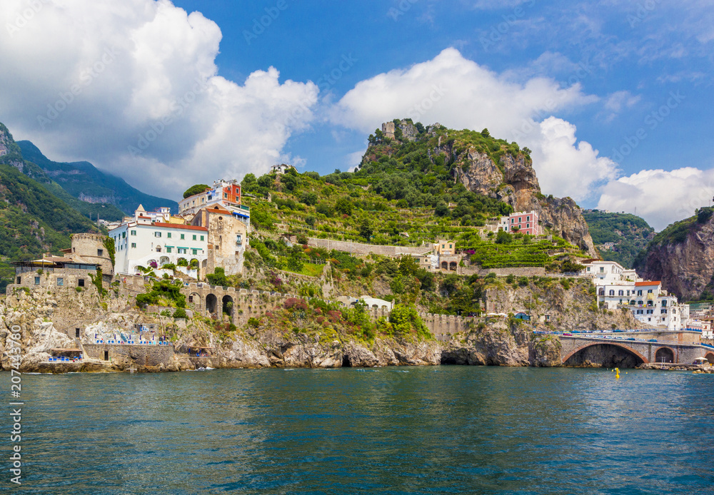 View of coastline Amalfi, beach, sea and mountains with colorful houses on slopes of small town of Amalfi Coast with Gulf of Salerno, Campania, Italy.