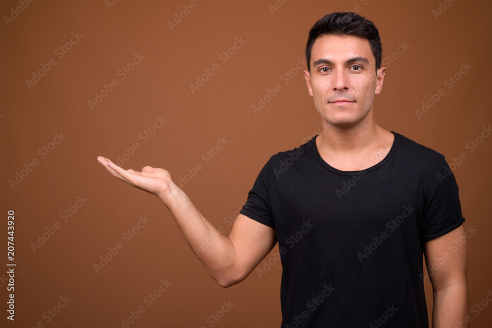Young handsome Hispanic man against brown background Young handsome Hispanic man against brown background