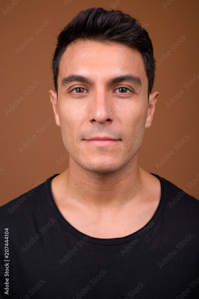 Fototapeta premium Young handsome Hispanic man against brown background
