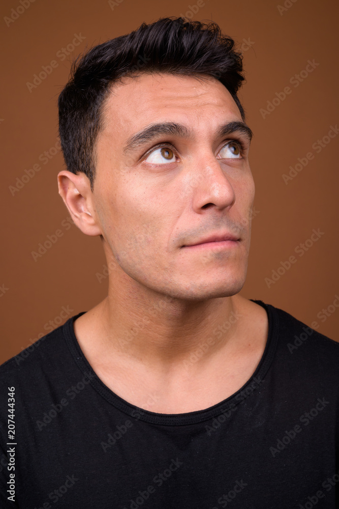 Fototapeta premium Young handsome Hispanic man against brown background