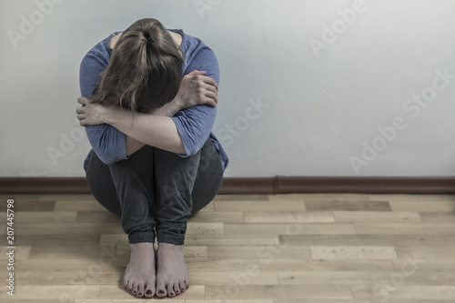 Depression with a woman. A sad girl is sitting in a room. Copy space.