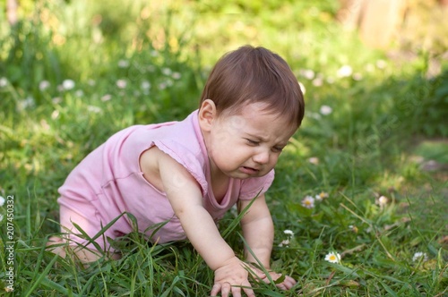 Baby is sitting on grass and crying. © siaivo