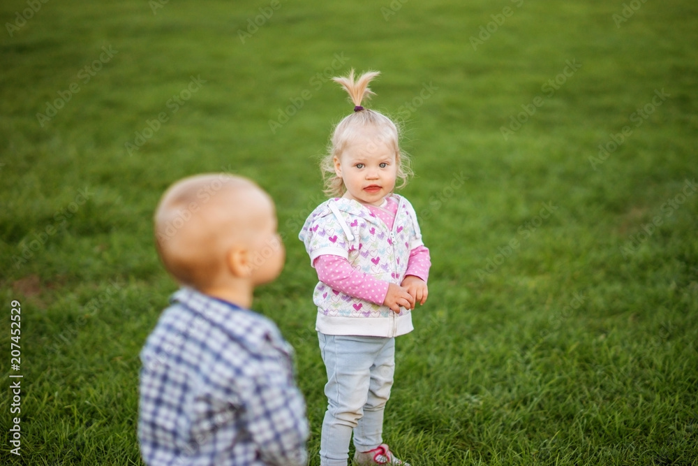 Kids boy and girl playing in the meadow on the green grass. Kids boy and girl playing in the meadow on the green grass.