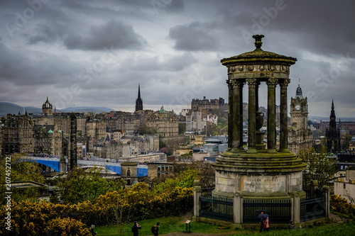 Edinburgh City and Castle, Scotland, viewed from Calton Hill on a cloudy afternoon with the Dugald Stewart monument in the foreground, Scott monument and Balmoral clock tower in background.