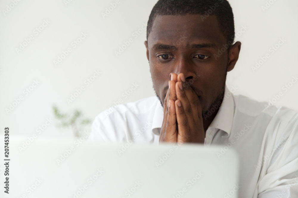 Thoughtful hopeful African American employee looking at computer laptop screen, waiting hoping, person holding hands in praying position, expecting trouble solution, positive result, close up portrait - obrazy, fototapety, plakaty 