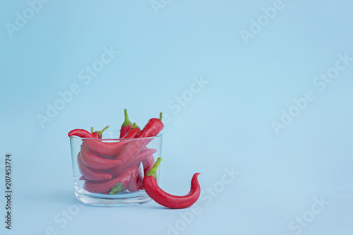 Red hot chilli pepper in glass jar on blue background photo