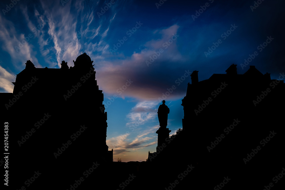 Silhouette of Statue and buildings in George Street, located in Edinburghs New Town, against a dark blue sky during sunset