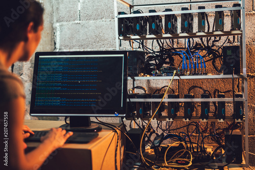 Programmer adjusting cryptocurrency mining rig to optimal operational settings