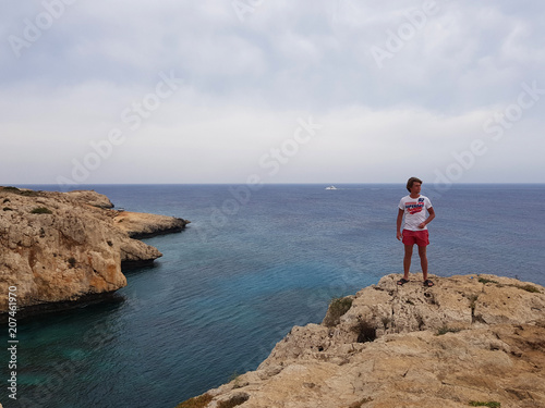 View to the sea, Cyprus, Protaras, May 2018. Beautiful blue sea. Rocks and mountains. It takes breath from this spectacle. A man stands on the edge of a rock and looks at this beauty