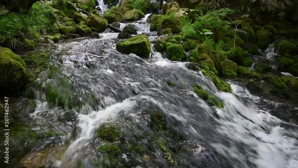Fast and clear mountain river flowing over rocks covered with moss Fast and clear mountain river flowing over rocks covered with moss