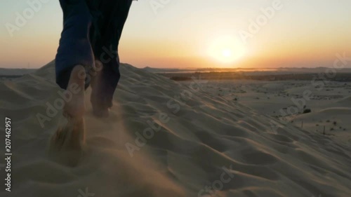 running up a hill sand dune in desert. running in sand dune in desert. two bare feet running in the sand