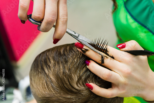 The hairdresser cuts the child. Haircut close-up.