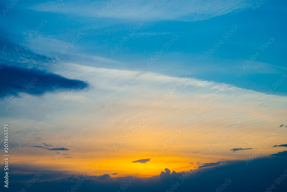 Beautiful early blue cloudy sky with orange sunlight. Atmospheric cobalt background of colorful sunrise with dense clouds and bright yellow sunny light for copy space. Cyan heaven above clouds.