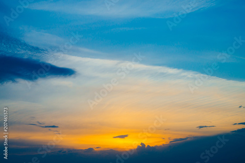 Beautiful early blue cloudy sky with orange sunlight. Atmospheric cobalt background of colorful sunrise with dense clouds and bright yellow sunny light for copy space. Cyan heaven above clouds.
