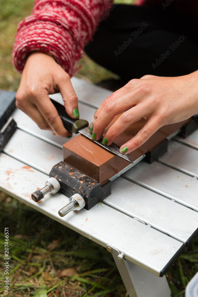 Woman sharpens a knife on a wet block outdoors Woman sharpens a knife on a wet block outdoors