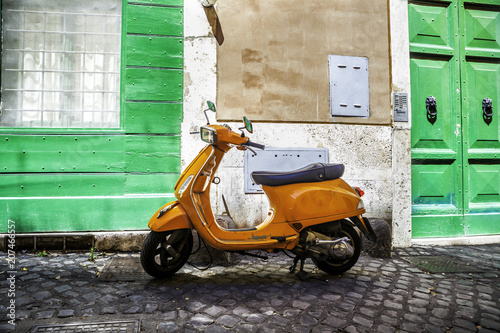 Obraz na płótnie Typical street scene in Rome with a red scooter on an old narrow cobblestoned street. Scooter Vespa parked on old street in Rome, Italy w salonie
