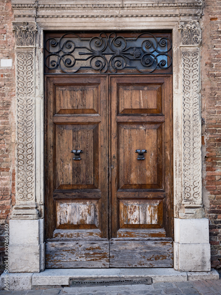 Old wooden portal with columns and architrave in white stone. Old wooden portal with columns and architrave in white stone.