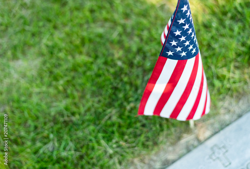 A single American flag placed at a veteran's gravesite marker