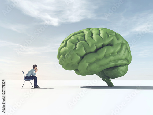 Man looking at a green brain in a field.