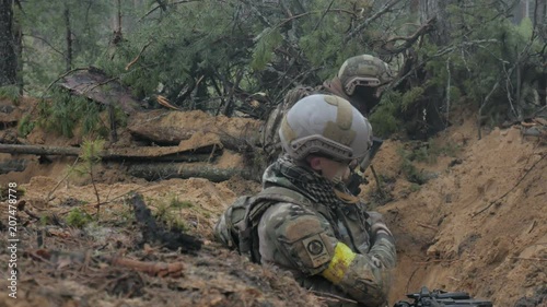 Soldiers in camouflage with combat weapons are being fired in the shelter of the forest, the military concept photo