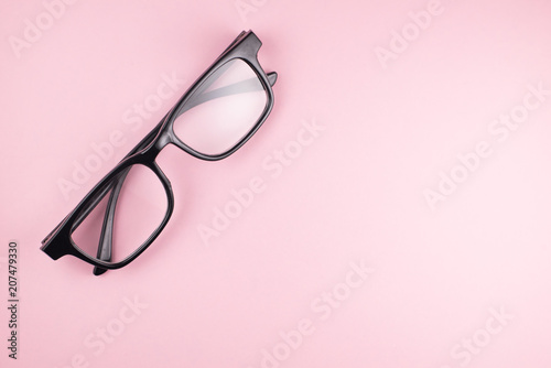 top view of reading glasses isolated on pink background with copy space. eye care and education concept
