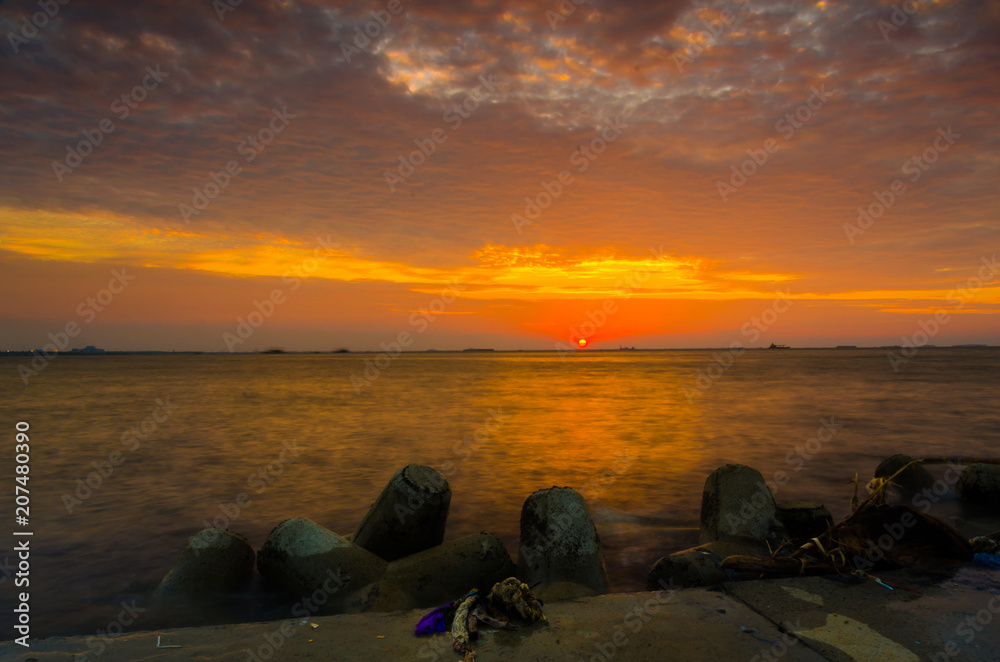 Enjoying beautiful colorful peaceful calm sunset at the horizon at a waterfront shorefront of Pantai Mutiara Jakarta Indonesia
