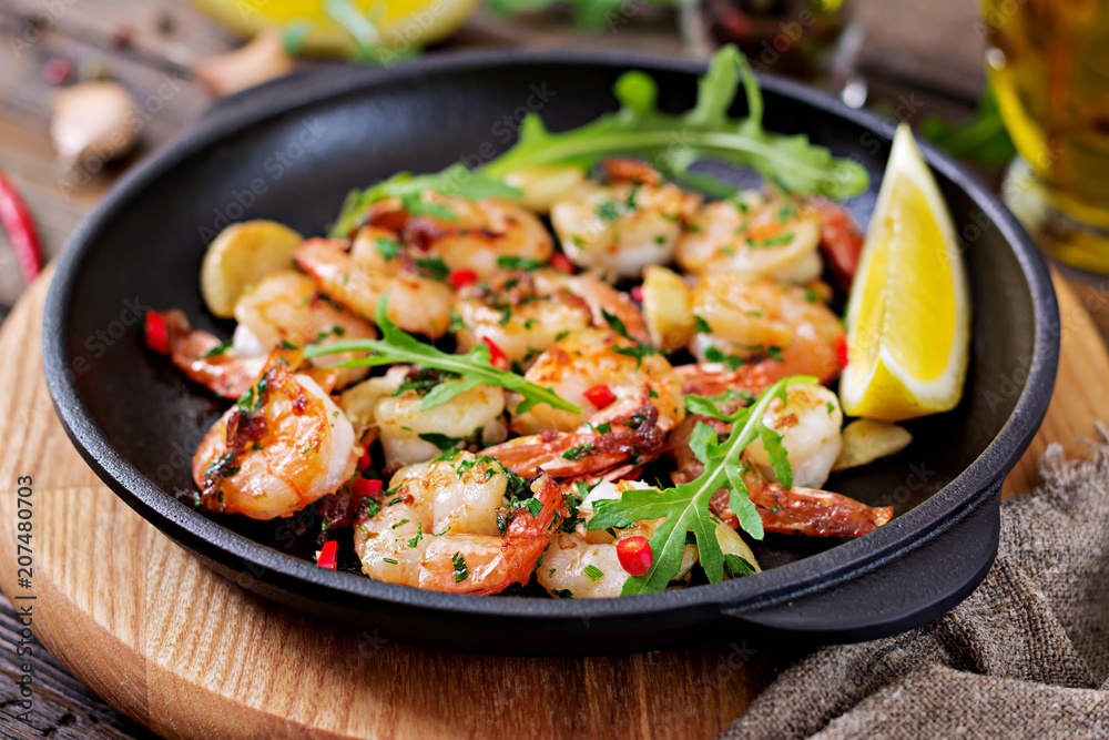 Prawns Shrimps roasted in garlic butter with lemon and parsley on wooden background. Healthy food. Prawns Shrimps roasted in garlic butter with lemon and parsley on wooden background. Healthy food.