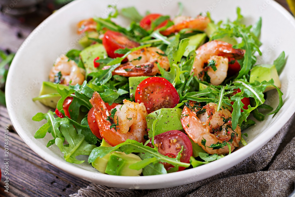 Fresh salad bowl with shrimp, tomato, avocado and arugula on wooden background close up. Healthy food. Clean eating. Fresh salad bowl with shrimp, tomato, avocado and arugula on wooden background close up. Healthy food. Clean eating.