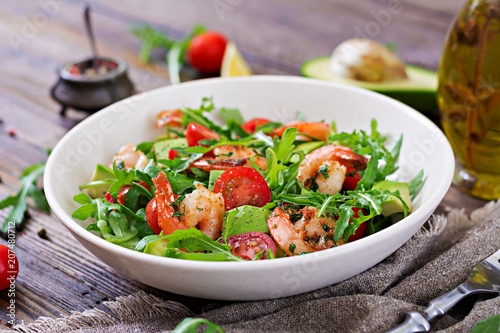 Fresh salad bowl with shrimp, tomato, avocado and arugula on wooden background close up. Healthy food. Clean eating. © timolina