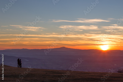 A couple looking at sunset from the top of a mountain