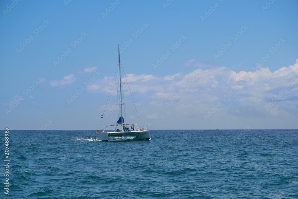 Sailing yacht catamaran sails on the waves in the warm Caribbean Sea. Sailboat. Sailing. Cancun Mexico. Summer sunny day, blue sky with clouds.