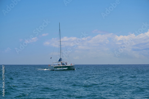 Sailing yacht catamaran sails on the waves in the warm Caribbean Sea. Sailboat. Sailing. Cancun Mexico. Summer sunny day, blue sky with clouds.