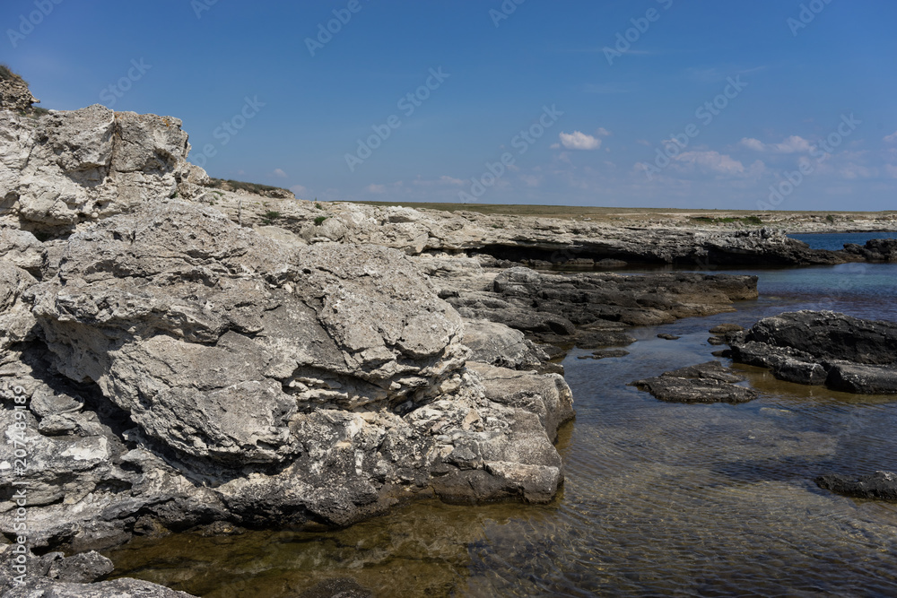 Rocks and stones on the background of the sea under the blue sky.