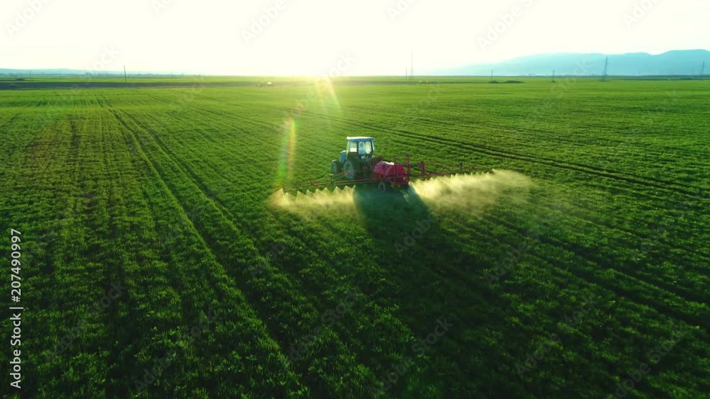 Aerial view of farming tractor plowing and spraying on field
