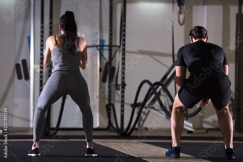 sports couple doing battle ropes cross fitness exercise
