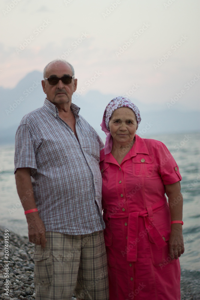 Portrait of elderly caucasian couple by the sea on background mountains