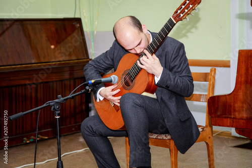 The guitarist performs a piece of music and puts his soul into it.