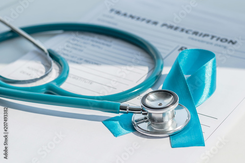Blue ribbon symbolic of prostate cancer awareness campaign and men's health on patients health record prescription form with doctor stethoscope. photo