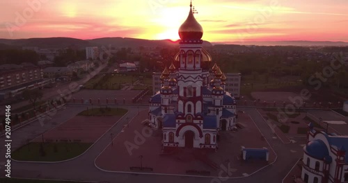 Aerial flying around new Church in small town. Christian temple and golden church dome at dawn. 4K photo