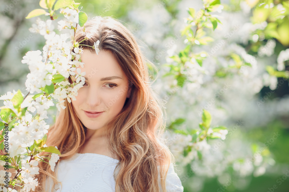 Close up romantic portrait of beautiful elegant woman in blossom spring trees.