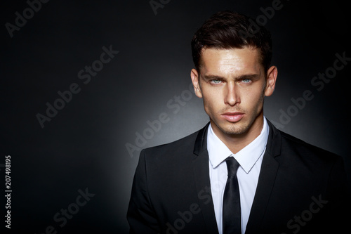 Portrait of a bussines man, wearing in black elegant suit looking at camera, isolated on black background. Horizontal view.