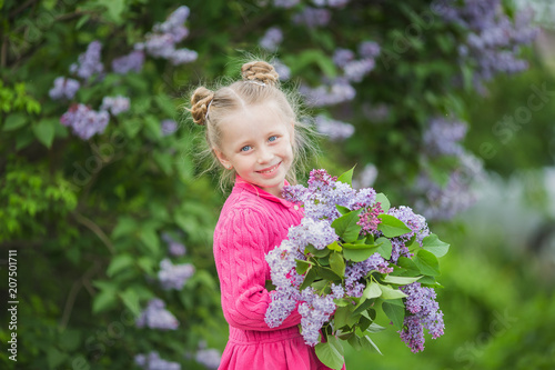 Cute beautiful girl with a bouquet of lilac in the park in the summer