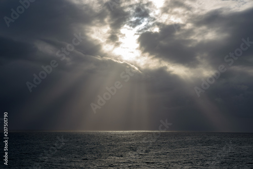 Dark clouds and sun rays on a sea. Sunlight. Madeira Island.