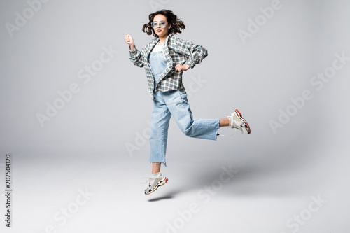 Fototapeta Naklejka Na Ścianę i Meble -  Full length portrait of a joyful young woman jumping and celebrating over gray background