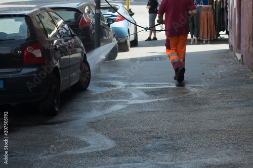 Horizontal View of a Dustman Cleaning the Street With a Water Pressure Machine