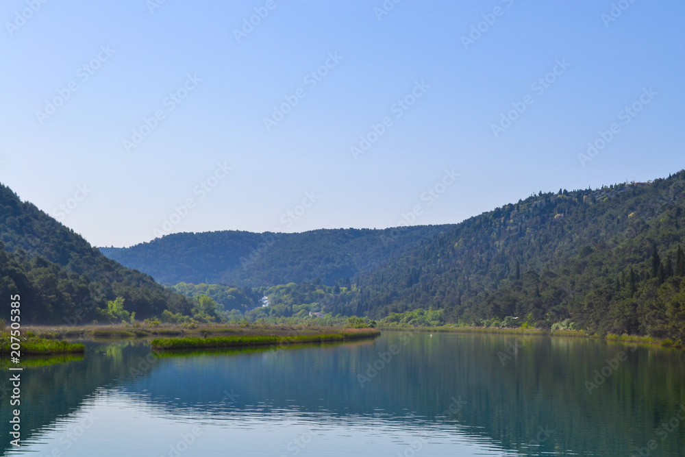 Scenic river valley background with green forests and water