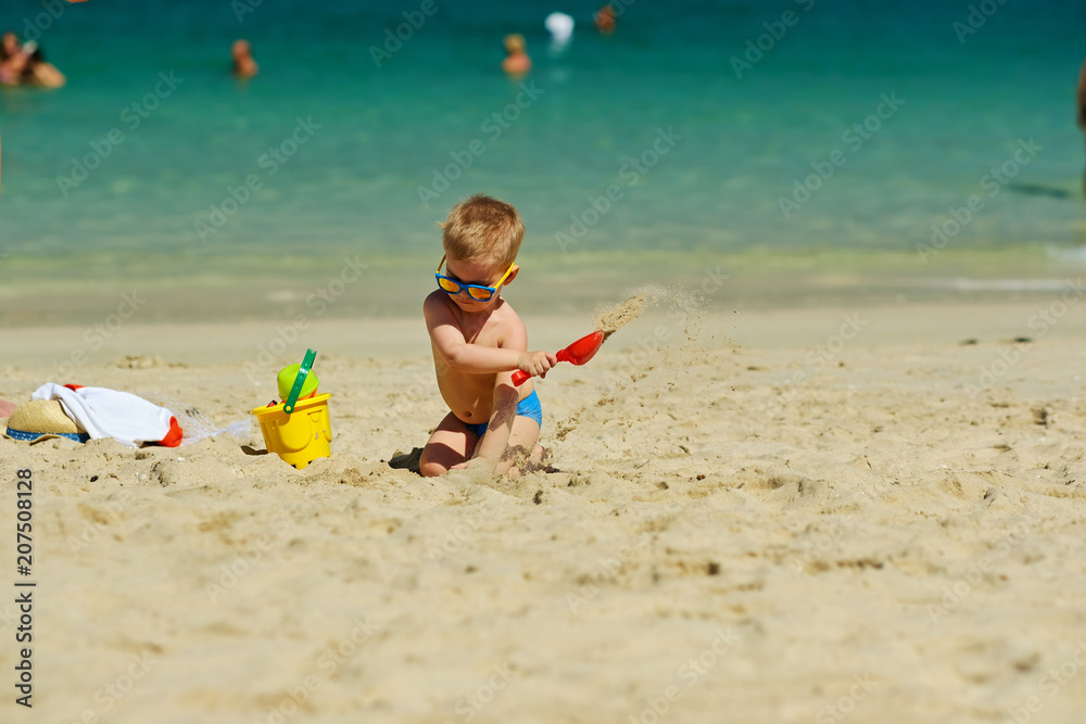 Toddler boy playing with shovel and sand on beach Toddler boy playing with shovel and sand on beach