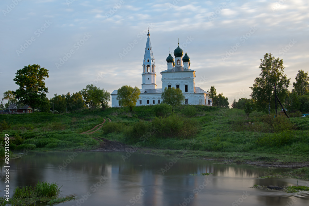 Sunrise in the tiny village Osenevo. Kazanska church reflects in a water of river Lakhost.