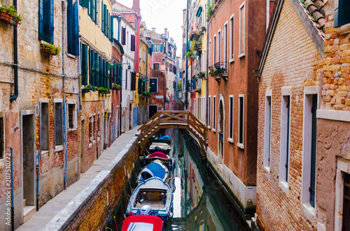 Narrow water lane river with old historical residential building houses and boats during sunrise in Venice Italy for romantic honeymoon holiday visit vacation