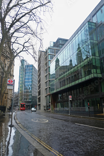 The exterior view on a street in London with bus and reflective buildings.